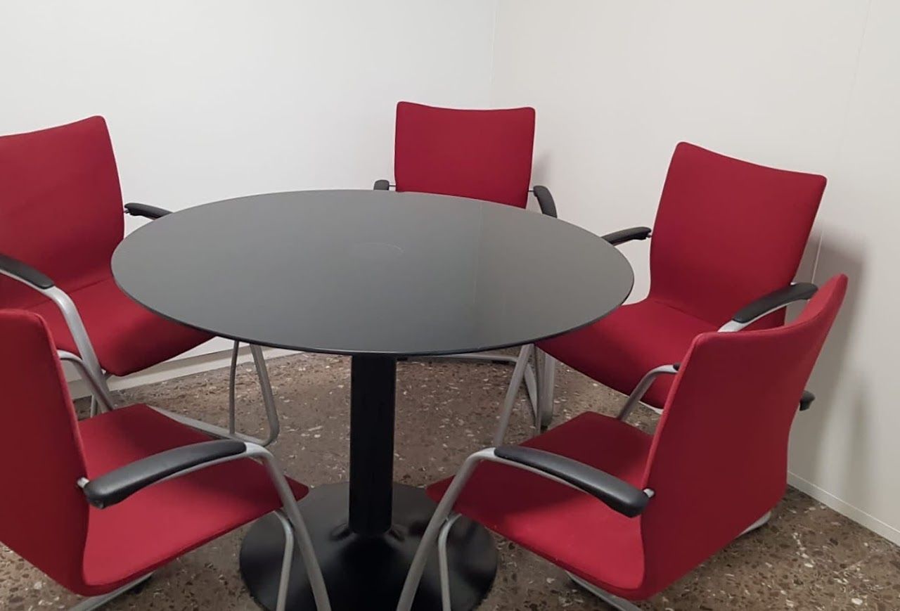 Sala de reuniones pequeña de 15 m² con mesa redonda y sillas rojas